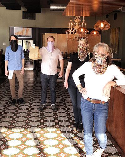 Ragazza employees wearing masks during COVID shutdown and holding a bag of carryout food.